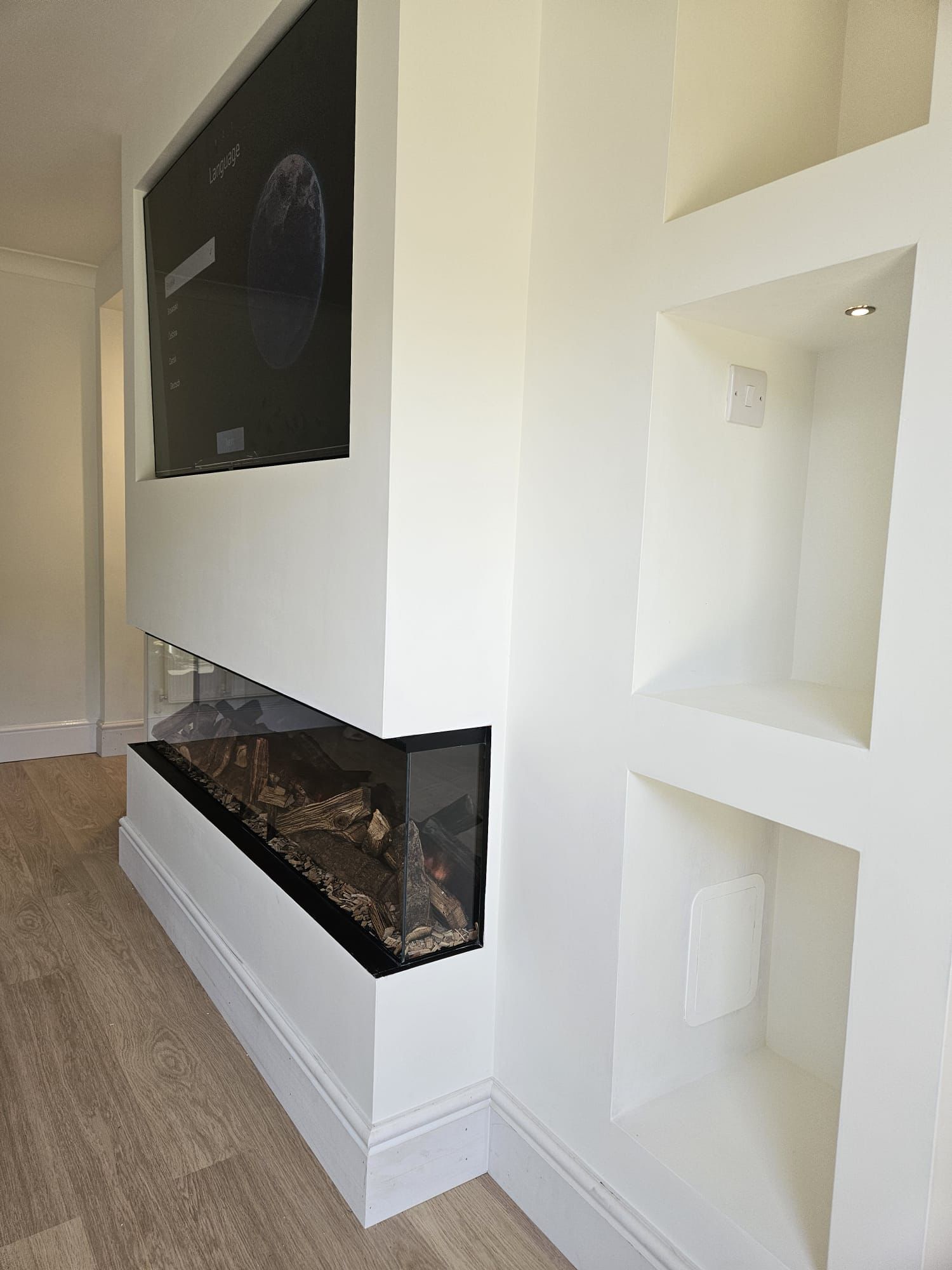 Finished media wall with electric fire lit and TV mounted, smooth plaster finish