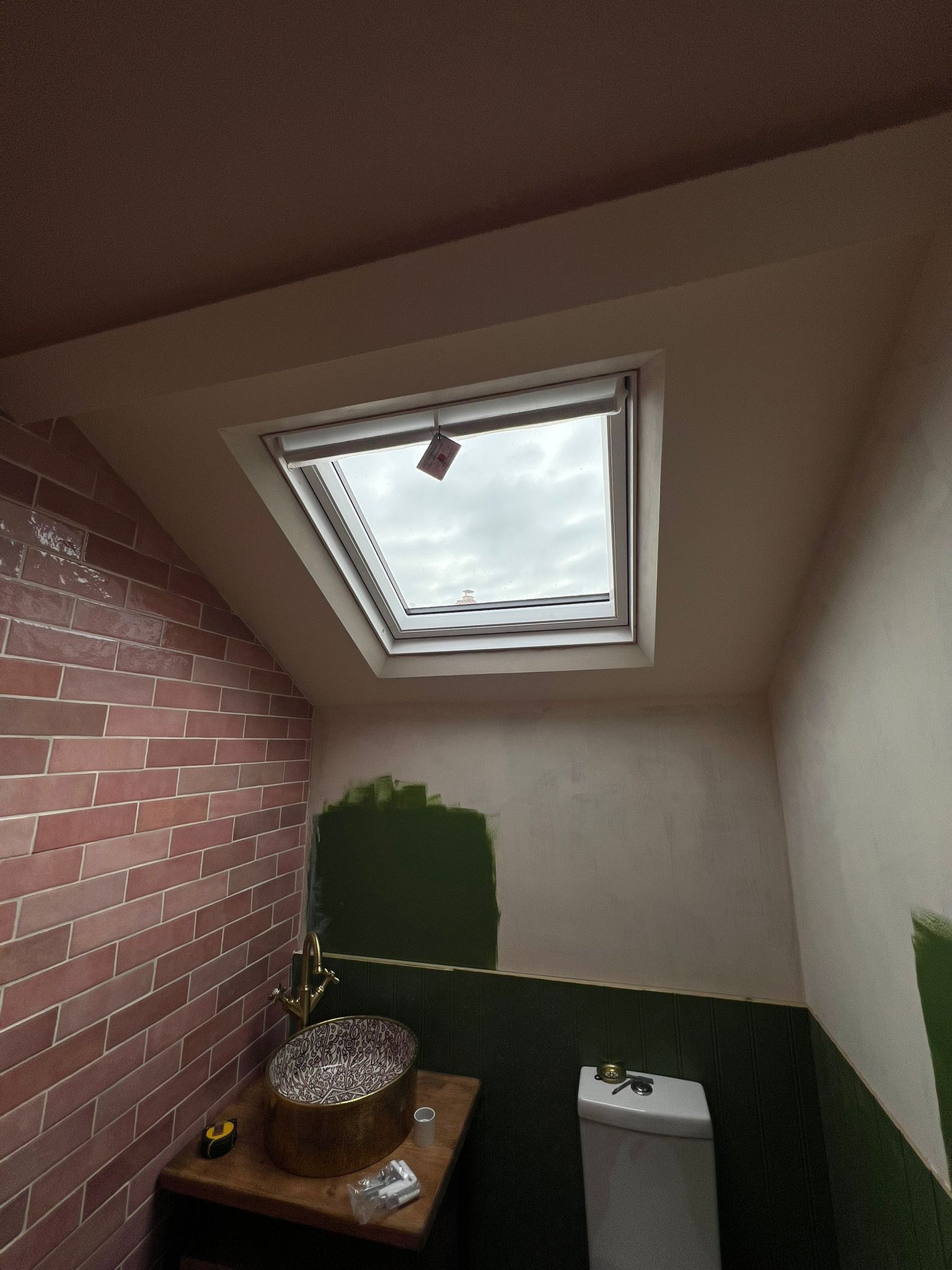 Loft bathroom with pink brick-effect tiles, skylight and brass basin