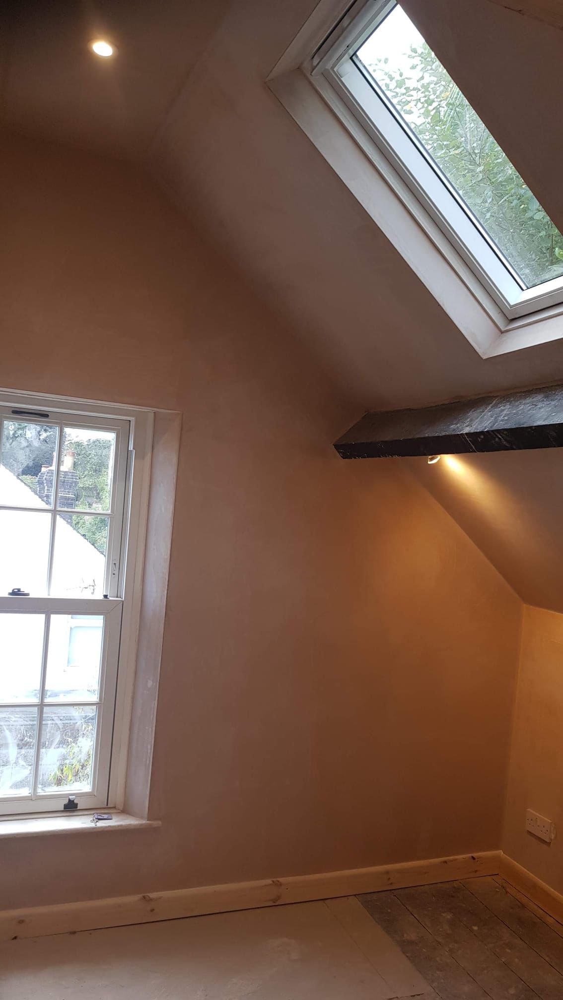 Freshly plastered loft room with exposed beam, skylight and cottage window