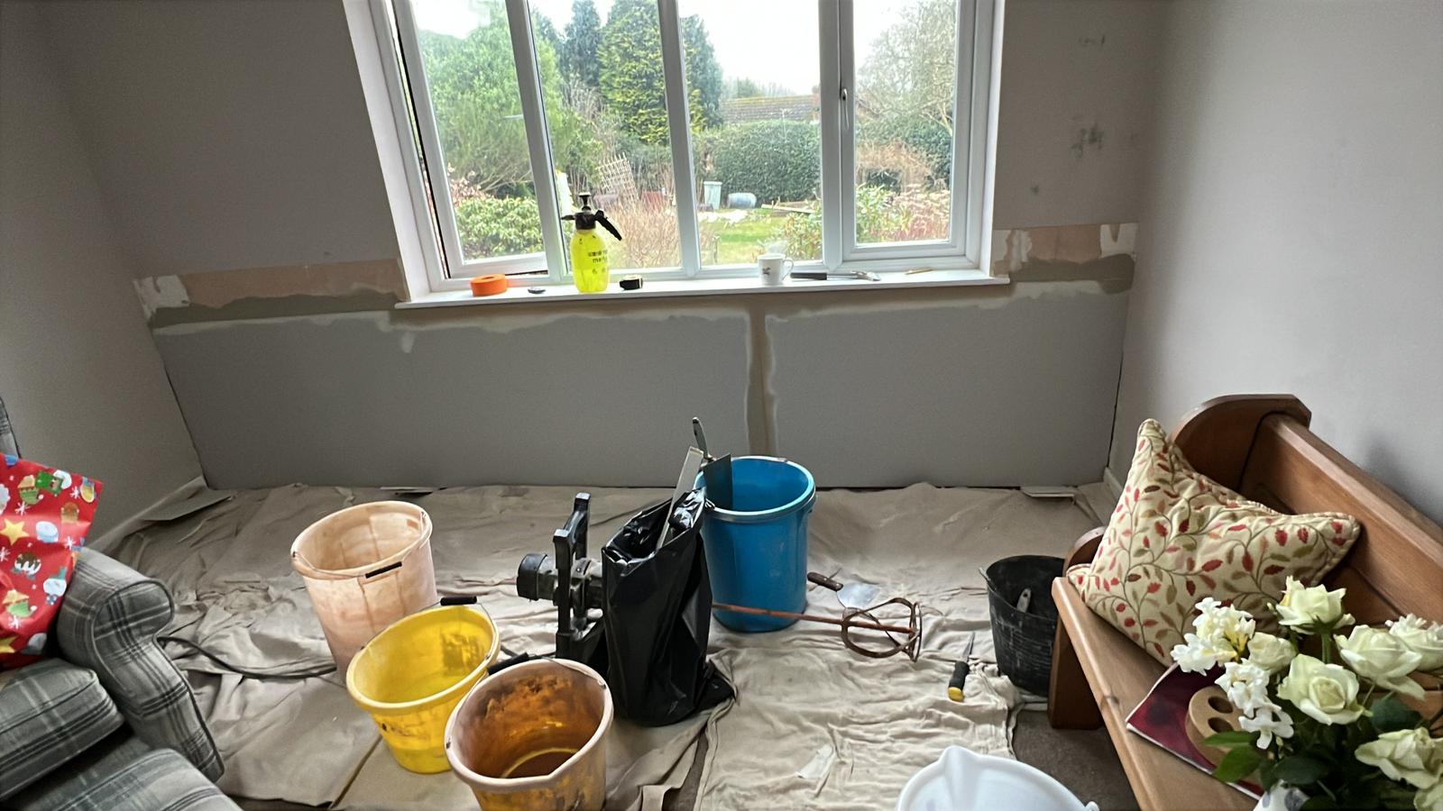 Room mid-plaster with dust sheets and garden view