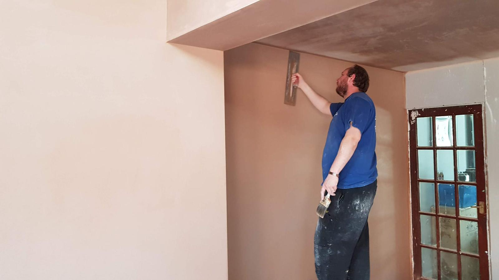 Plasterer smoothing freshly plastered wall with trowel