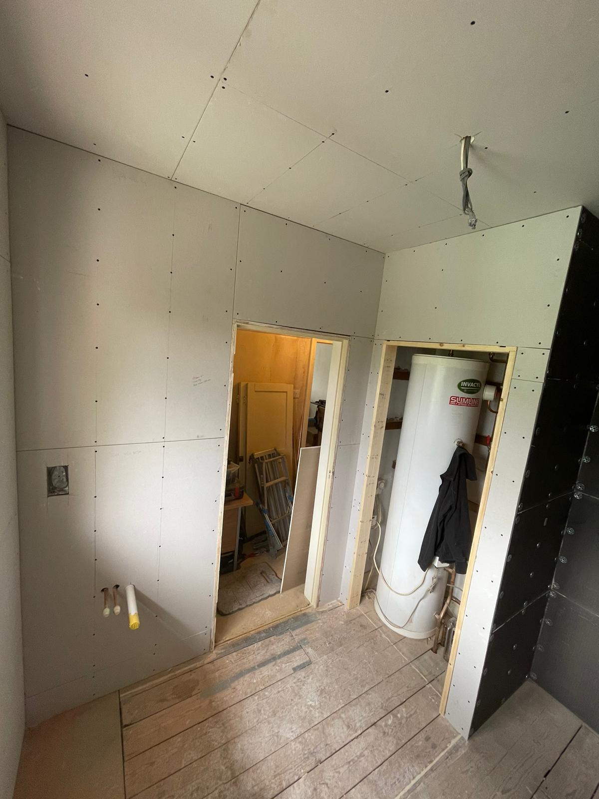 Room boarded with plasterboard, doorways and hot water cylinder cupboard